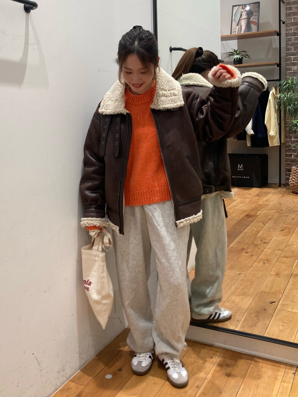 グレー系のスウェットパンツ、レッド系のトートバッグ、ブラウン系のブルゾンを着用したレディースの冬コーディネートの1枚目の写真