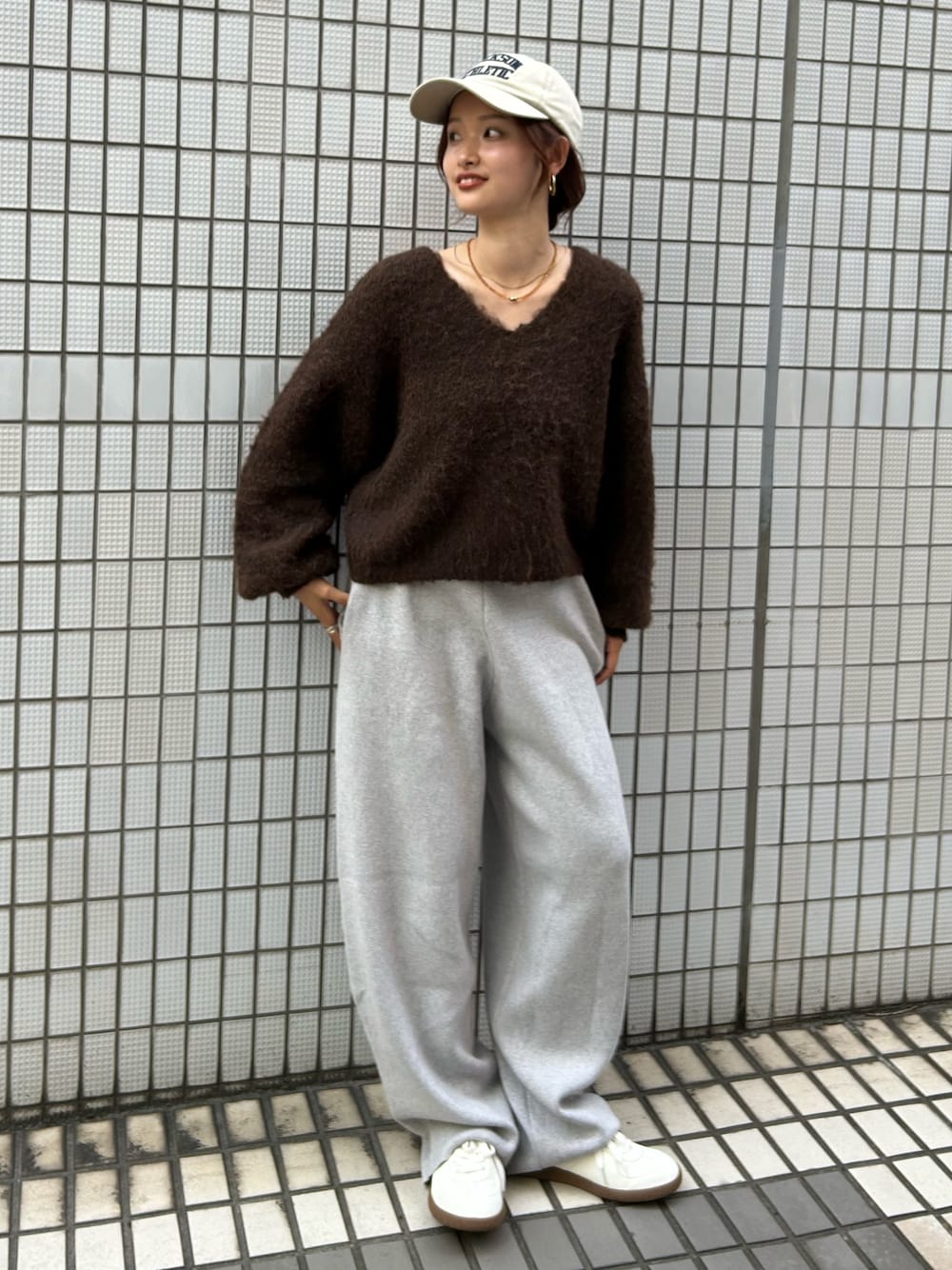 ホワイト系のスニーカー、ブラウン系のニット/セーター、グレー系のその他パンツを着用したレディースの秋コーディネートの1枚目の写真