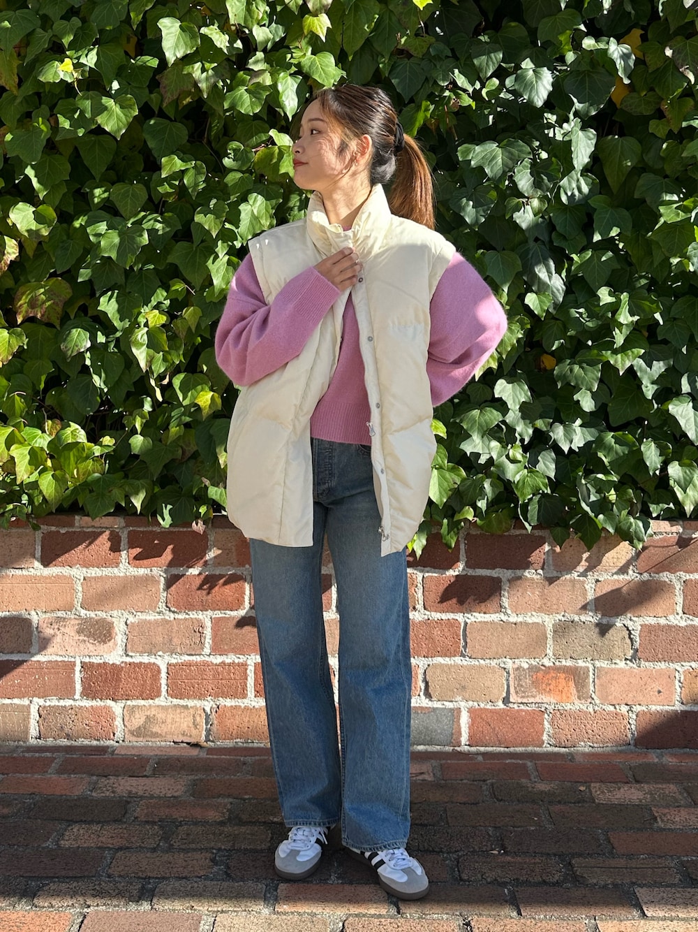 ブルー系のデニムパンツ、ピンク系のニット/セーター、ホワイト系のダウンジャケット/コートを着用したレディースの冬コーディネートの1枚目の写真