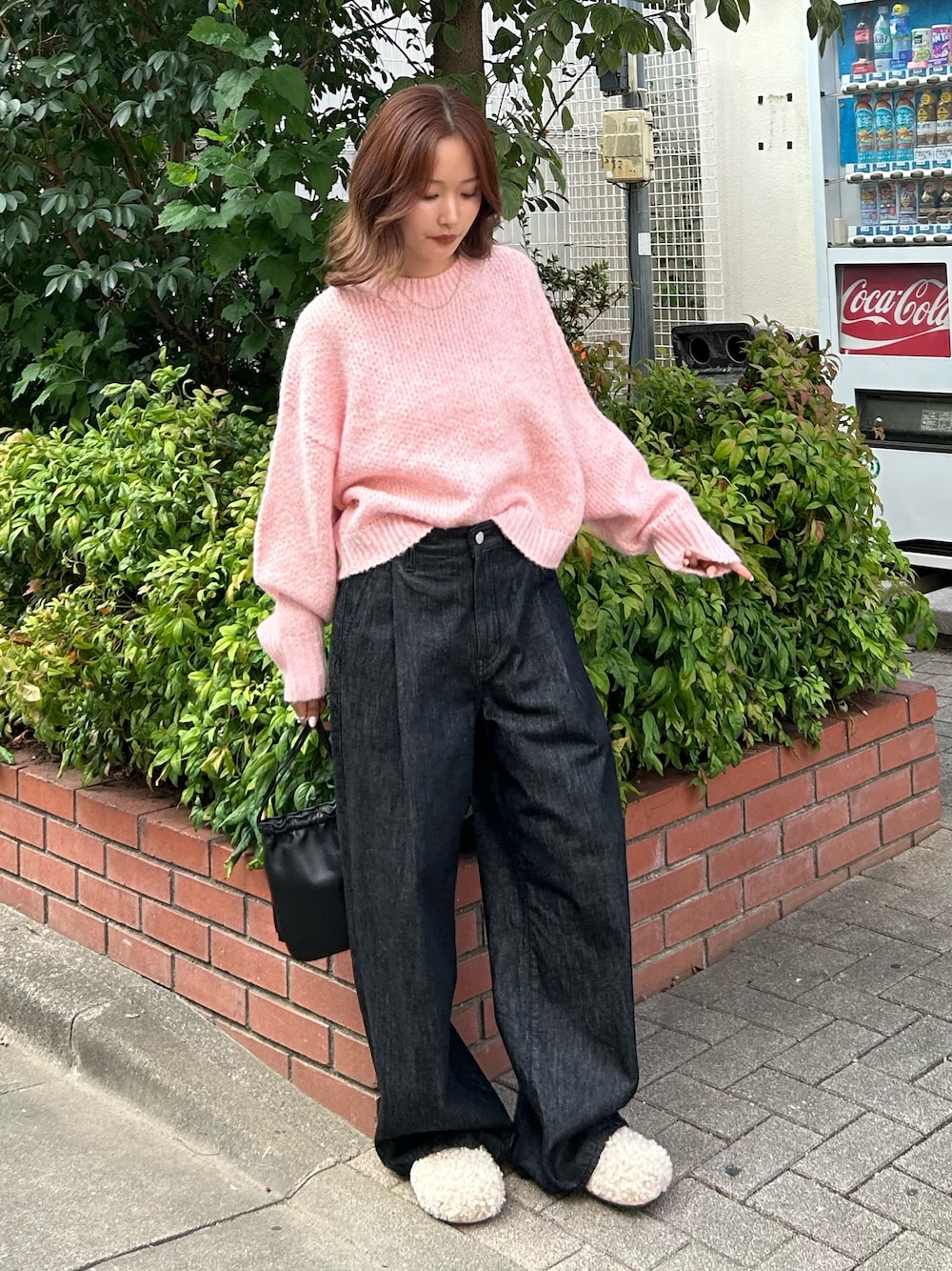 ピンク系のニット/セーター、ブラック系のデニムパンツ、ブラック系のショルダーバッグを着用したレディースの秋コーディネートの1枚目の写真