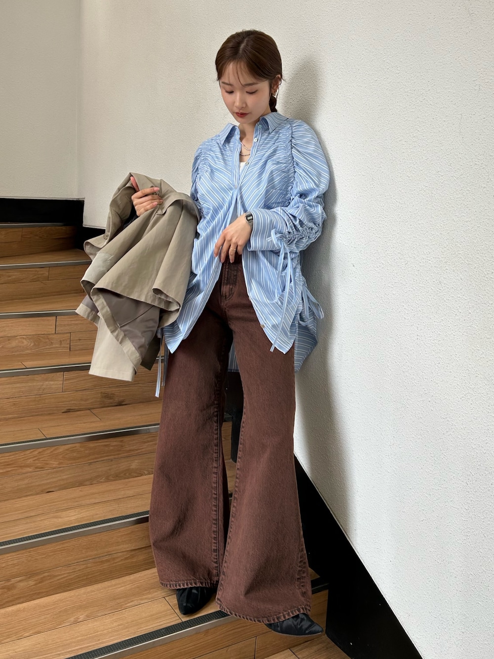 グリーン系のトレンチコート、ブラック系のパンプス、ブルー系のシャツ/ブラウスを着用したレディースの春コーディネートの1枚目の写真