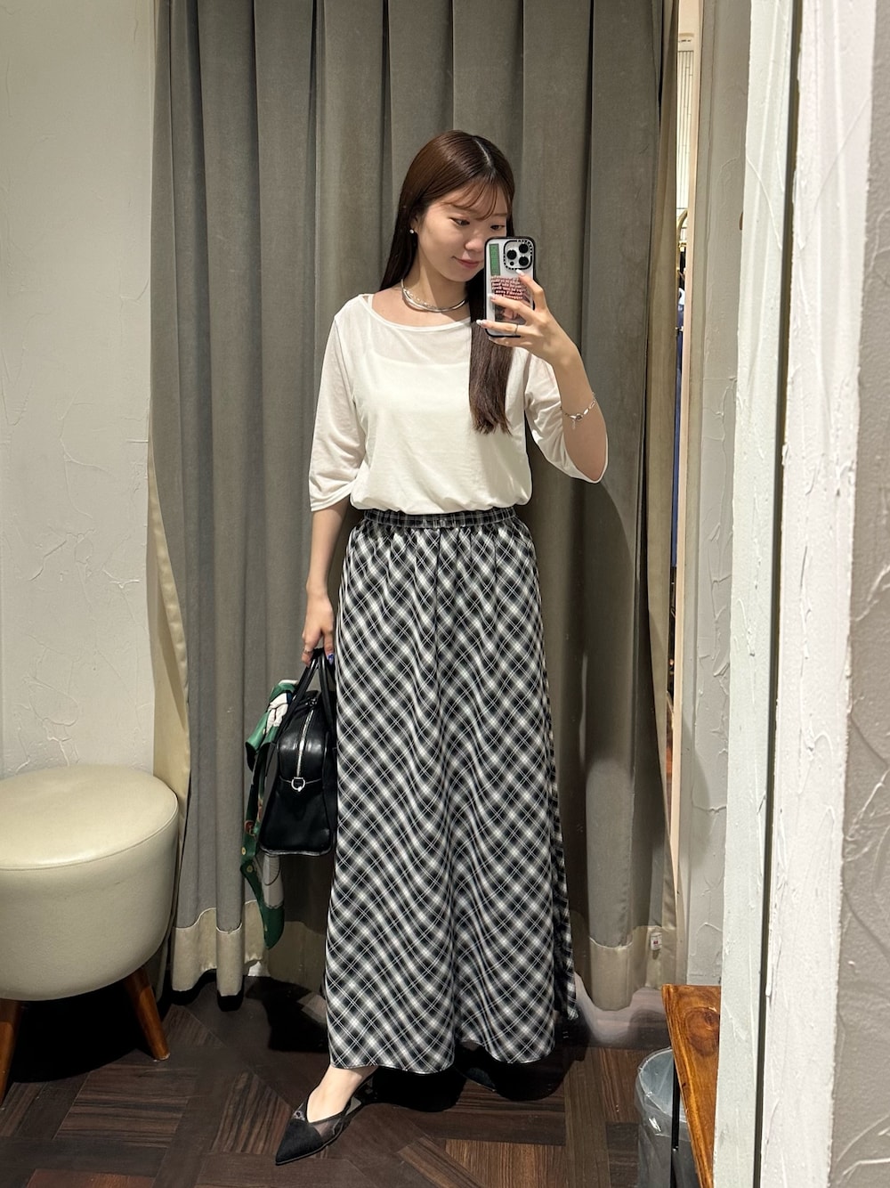 ブラック系のスカート、ホワイト系のTシャツ/カットソー、ブラック系のボストンバッグを着用したレディースの夏コーディネートの1枚目の写真