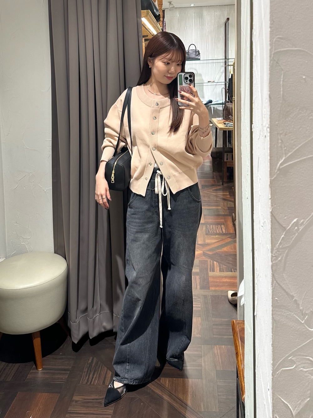 ブラック系のデニムパンツ、ピンク系のカーディガン/ボレロ、ブラック系のショルダーバッグを着用したレディースの秋コーディネートの1枚目の写真