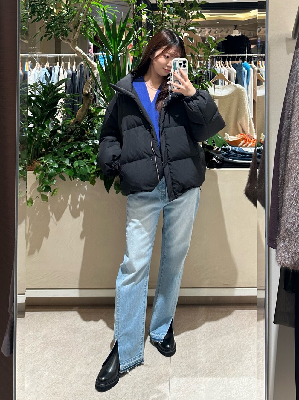 ブルー系のニット/セーター、ブルー系のデニムパンツ、ブラック系のダウンジャケット/コートを着用したレディースの冬コーディネートの1枚目の写真
