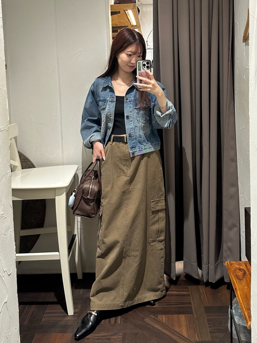 ブラウン系のスカート、ブルー系のデニムジャケット、ブラウン系のボストンバッグを着用したレディースの秋コーディネートの1枚目の写真