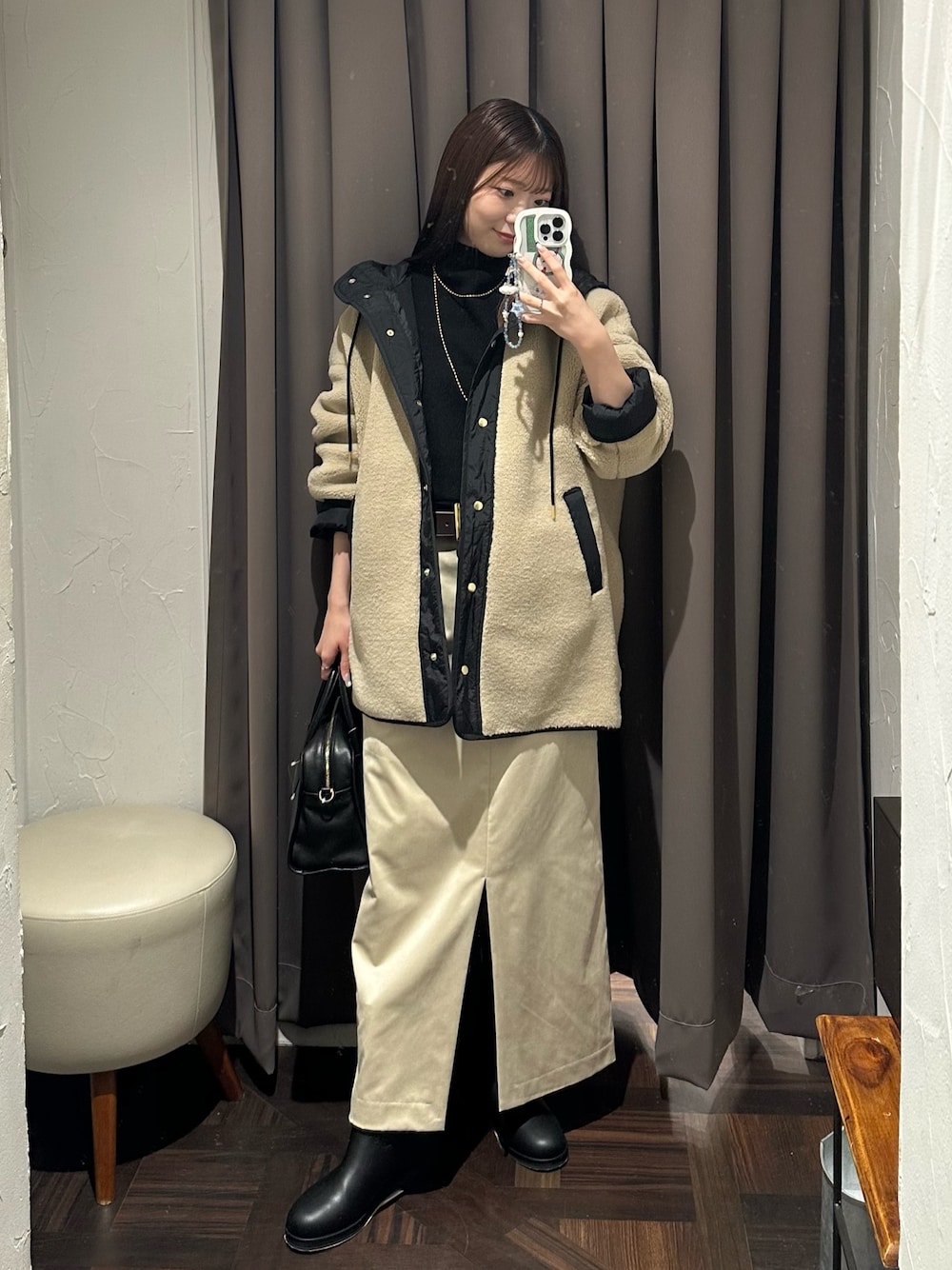 ベージュ系のその他アウター、ベージュ系のスカート、ブラック系のボストンバッグを着用したレディースの秋コーディネートの1枚目の写真