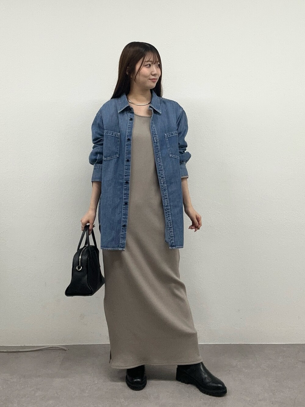 ベージュ系のワンピース、ブラック系のボストンバッグ、ブラック系のブーツを着用したレディースの秋コーディネートの1枚目の写真