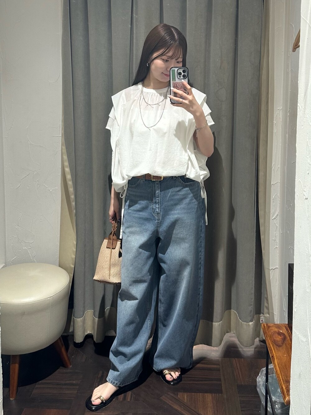 ブルー系のデニムパンツ、ホワイト系のシャツ/ブラウス、ブラウン系のハンドバッグを着用したレディースの夏コーディネートの1枚目の写真