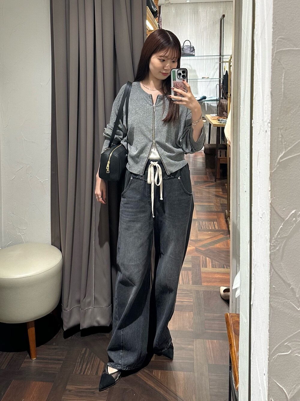 ブラック系のデニムパンツ、ブラック系のカーディガン/ボレロ、ブラック系のパンプスを着用したレディースの秋コーディネートの1枚目の写真