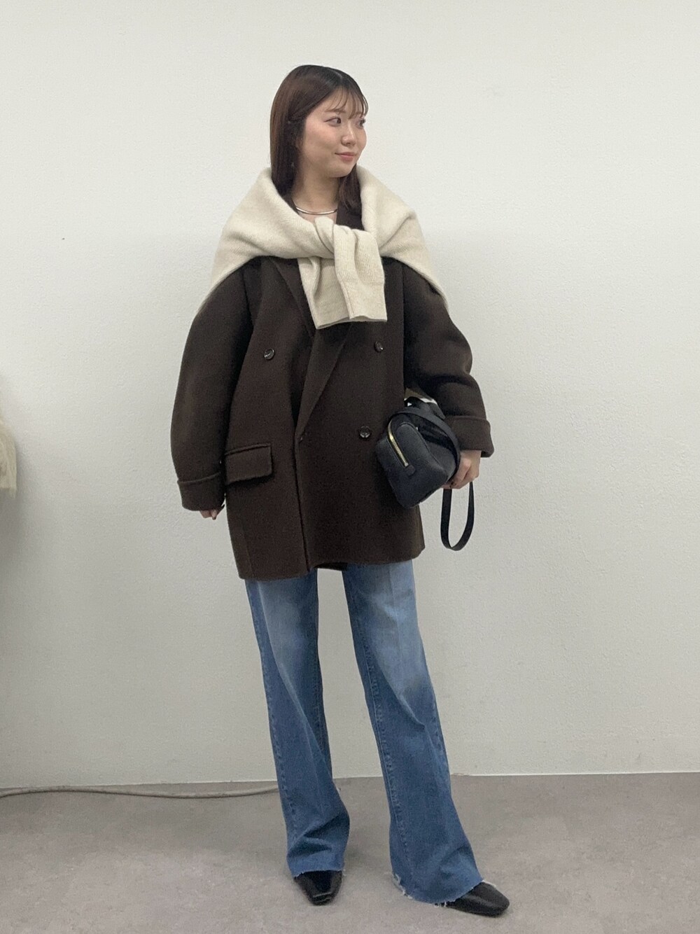 ブラウン系のその他アウター、ブルー系のデニムパンツ、ベージュ系のニット/セーターを着用したレディースの秋コーディネートの1枚目の写真