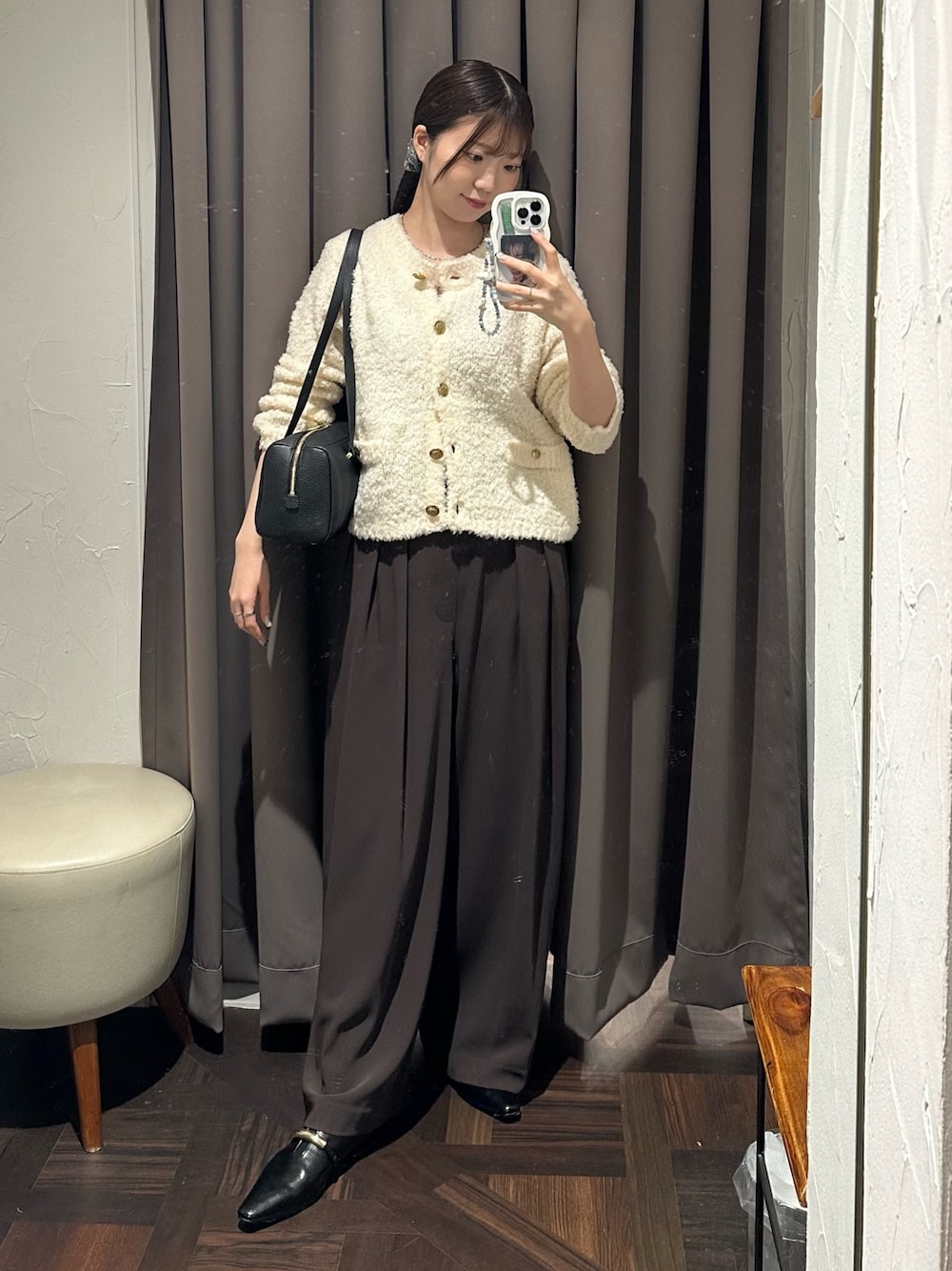 ブラウン系のスラックス、ホワイト系のカーディガン/ボレロ、ブラック系のショルダーバッグを着用したレディースの秋コーディネートの1枚目の写真