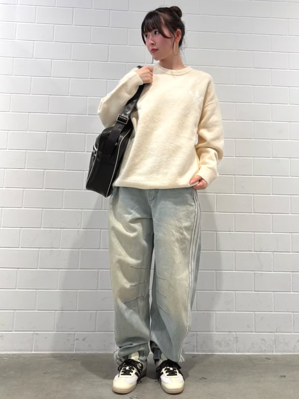 ブルー系のデニムパンツ、ホワイト系のニット/セーター、ブラウン系のバッグを着用したレディースの秋コーディネートの1枚目の写真