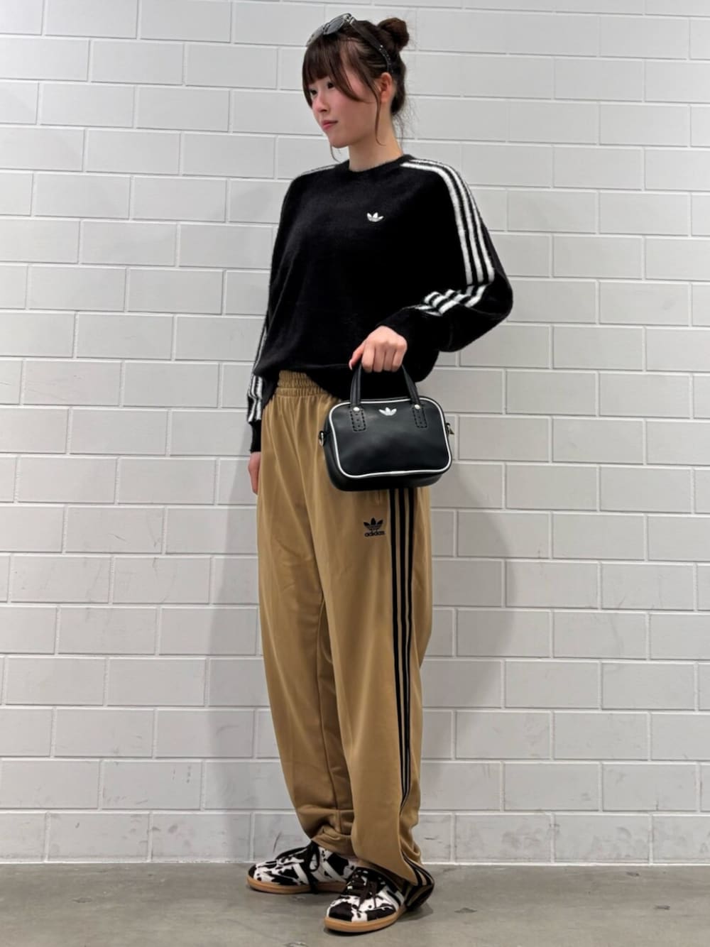 ブラック系のショルダーバッグ、ブラウン系のスニーカー、ブラック系のニット/セーターを着用したレディースの秋コーディネートの1枚目の写真