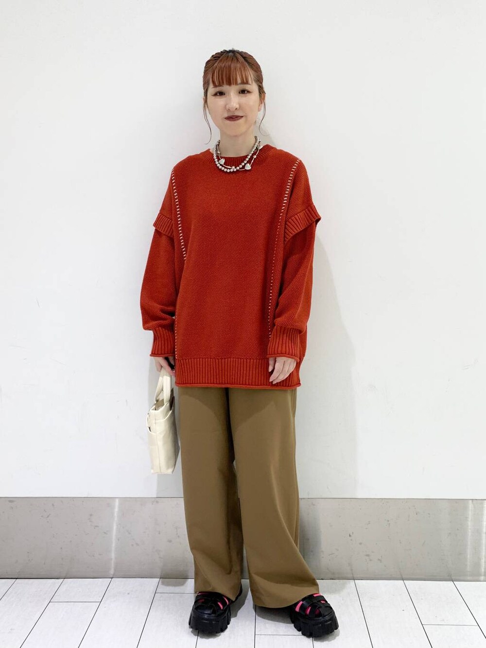 レッド系のTシャツ/カットソー、ホワイト系のショルダーバッグ、ベージュ系のその他パンツを着用したレディースの秋コーディネートの1枚目の写真