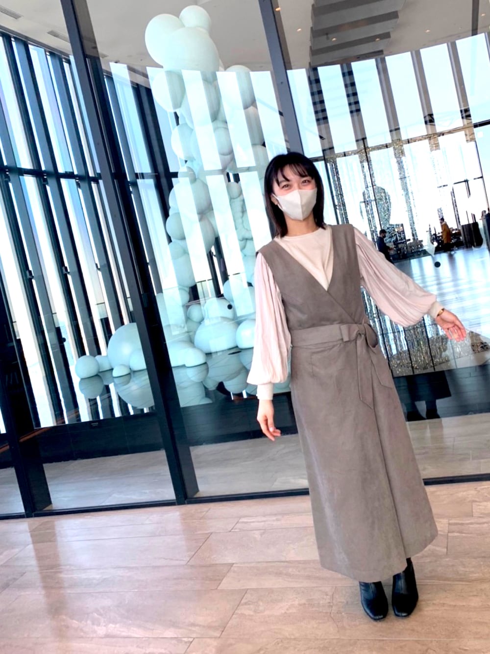 ブラウン系のワンピース、ホワイト系のニット/セーター、ブラック系のブーツを着用したレディースの冬コーディネートの1枚目の写真