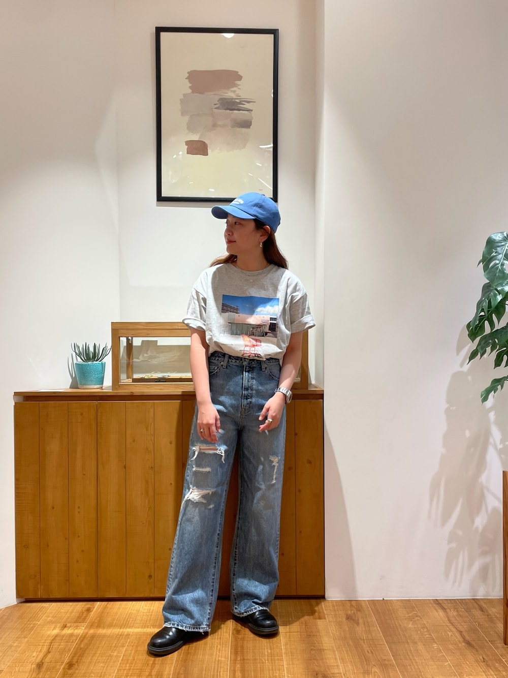 グレー系のTシャツ/カットソー、ブルー系のデニムパンツ、ブルー系のキャップを着用したレディースの春コーディネートの1枚目の写真