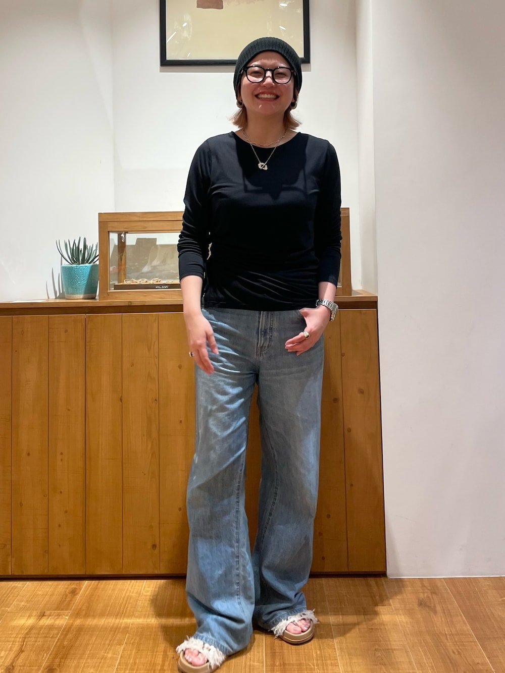 ブラック系のTシャツ/カットソー、ブルー系のデニムパンツ、ホワイト系のサンダルを着用したレディースの春コーディネートの1枚目の写真
