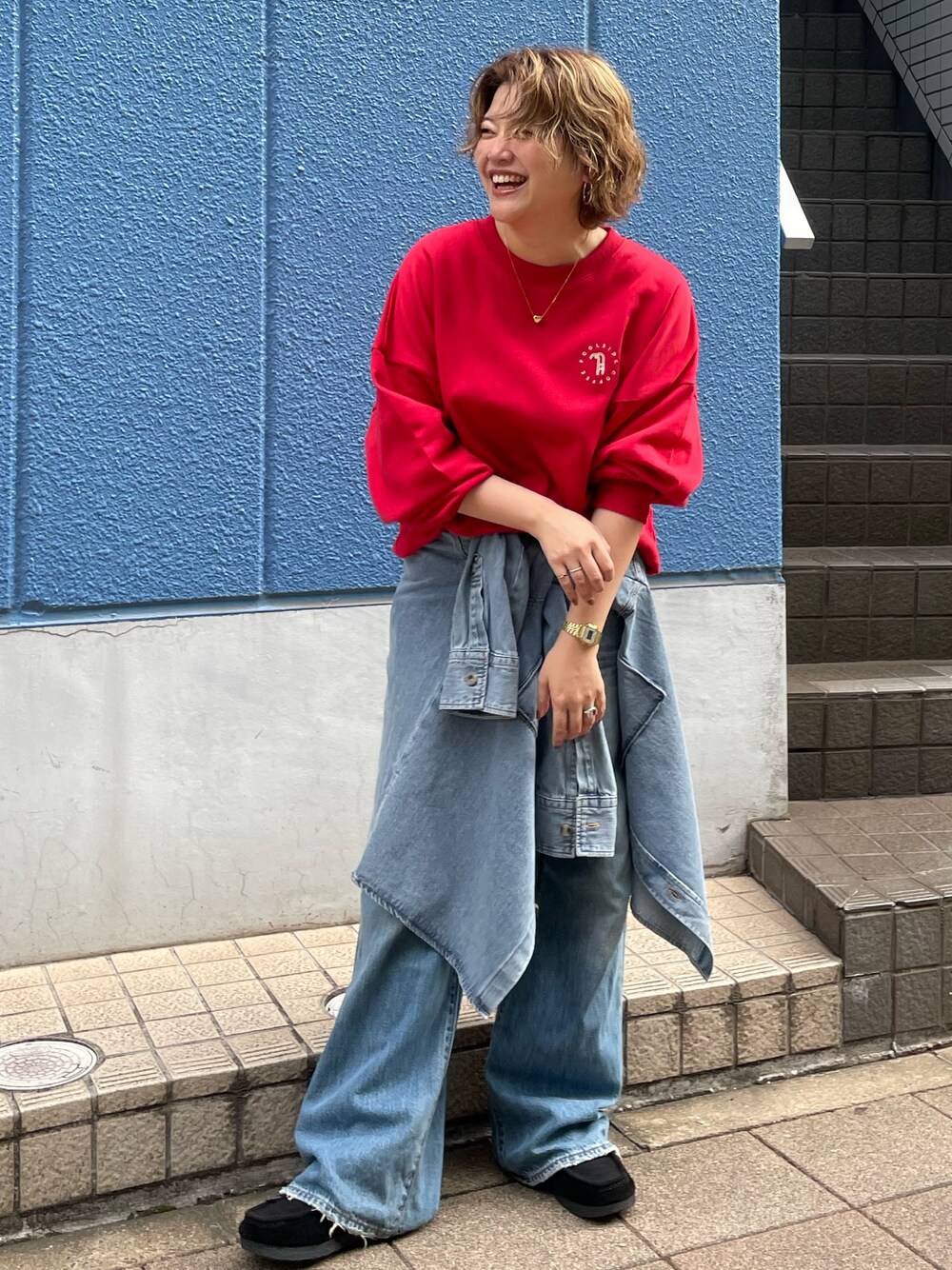 レッド系のスウェット、ブルー系のシャツ/ブラウス、ブルー系のデニムパンツを着用したレディースの秋コーディネートの1枚目の写真