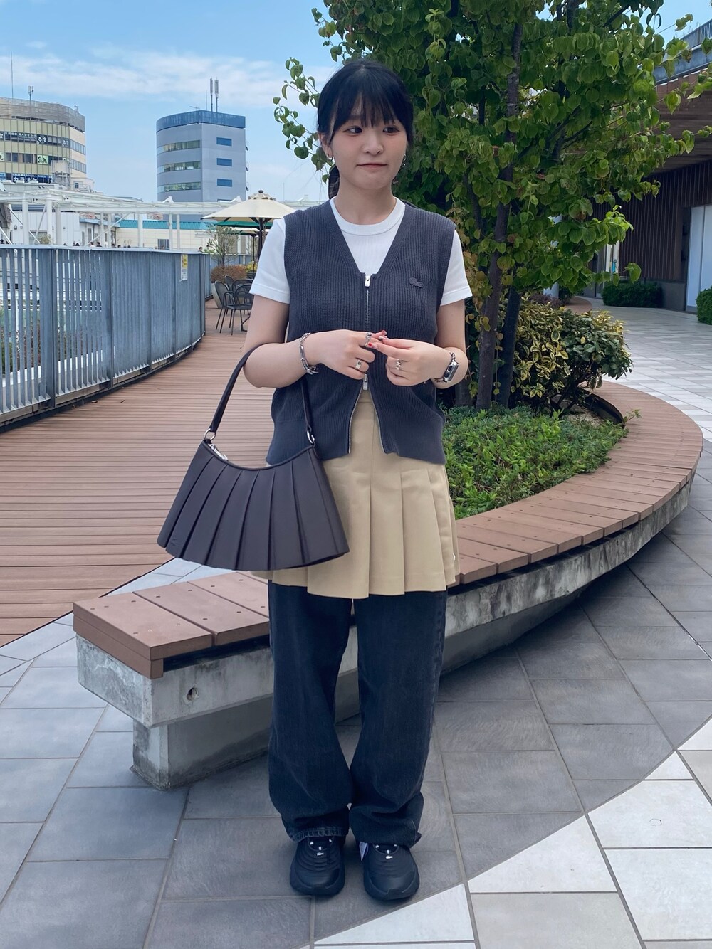 グレー系のベスト、ホワイト系のTシャツ/カットソー、ベージュ系のスカートを着用したレディースの秋コーディネートの1枚目の写真