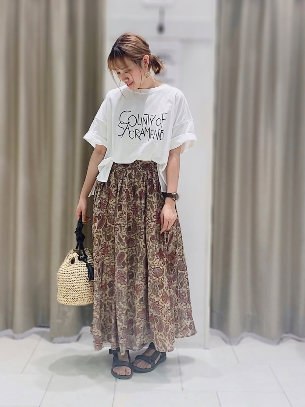 ベージュ系のショルダーバッグ、ホワイト系のTシャツ/カットソー、ベージュ系のスカートを着用したレディースの夏コーディネートの1枚目の写真