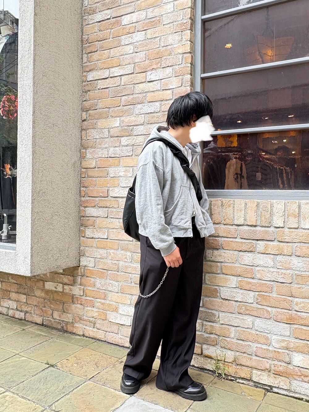 グレー系のパーカー、ブラック系のスラックス、ブラック系のショルダーバッグを着用したメンズの春コーディネートの1枚目の写真