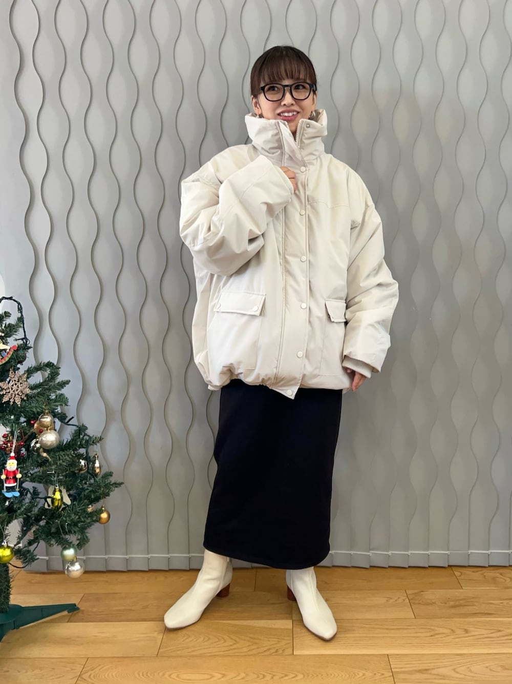 ホワイト系のブルゾン、ホワイト系のブーツ、ブラック系のスカートを着用したレディースの冬コーディネートの1枚目の写真