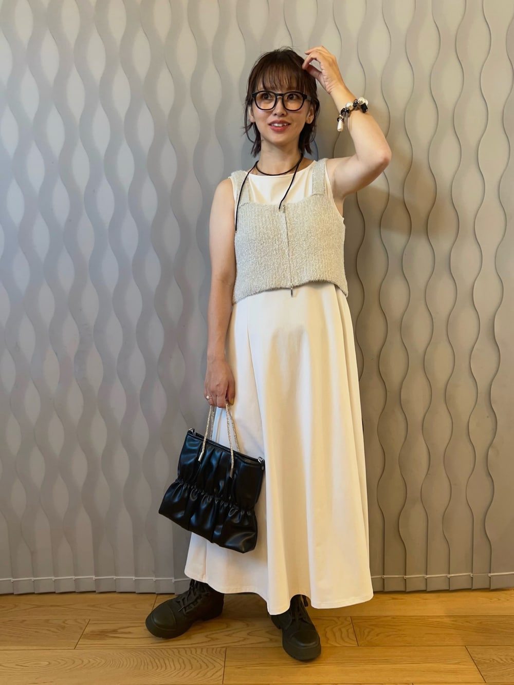 ホワイト系のベスト、ホワイト系のワンピース/ドレス、ブラック系のハンドバッグを着用したレディースの秋コーディネートの1枚目の写真