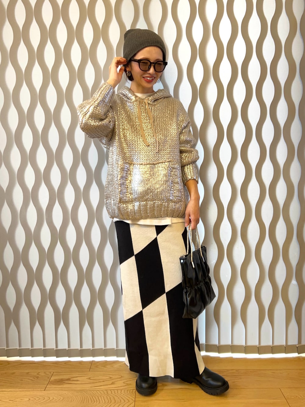 シルバー系のニット/セーター、ブラック系のハンドバッグ、ブラック系のスカートを着用したレディースの冬コーディネートの1枚目の写真