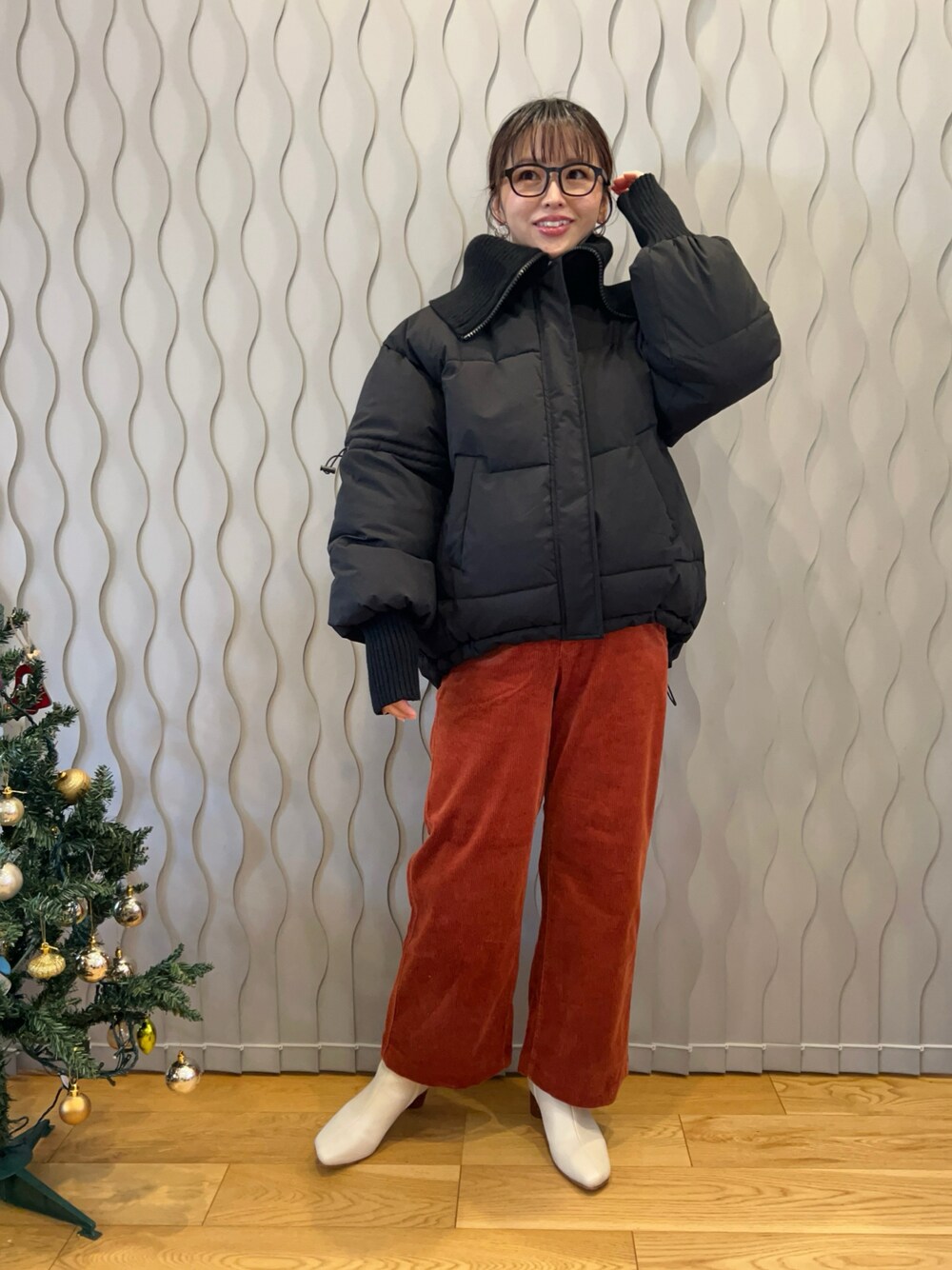 ブラック系のダウンジャケット/コート、オレンジ系のパンツ、ホワイト系のブーツを着用したレディースの冬コーディネートの1枚目の写真