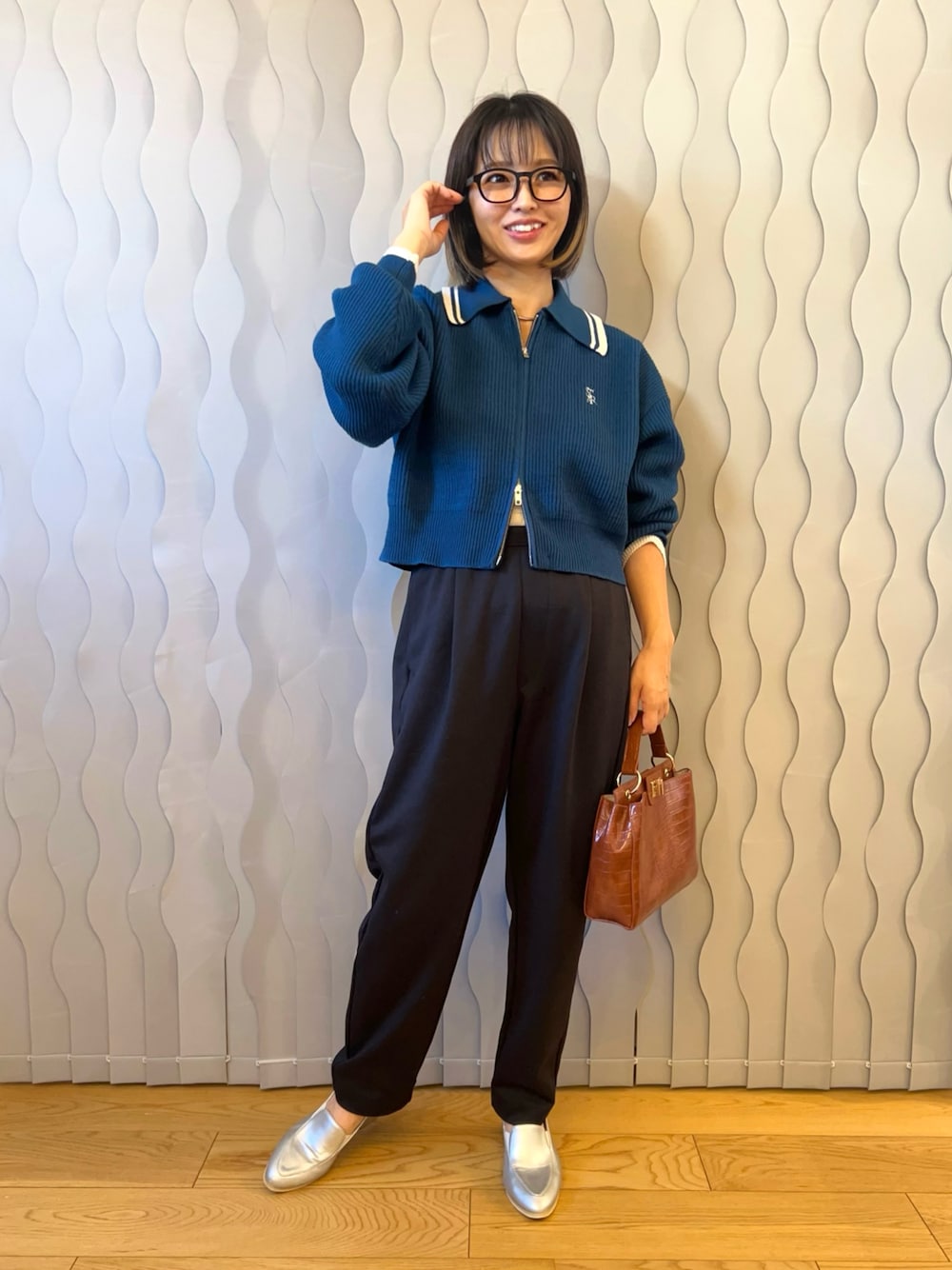 ブルー系のニット/セーター、ブラック系のパンツ、ブラウン系のハンドバッグを着用したレディースの秋コーディネートの1枚目の写真
