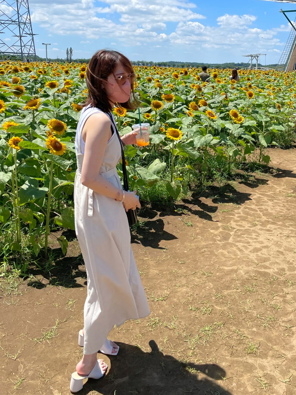 「ラクチンコーデ、ワンピース、白ワンピース、白、ひまわり畑、ノースリーブ、夏コーデ、夏、サンダル」｜「BONLECILLのサイドベルト付きフレアジャンパースカート（ジャンパースカート、ホワイト系）」を使った、いぬのさん（レディース・157cm）の夏コーディネートの1枚目の写真