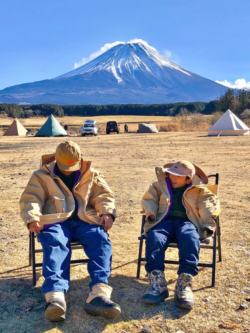 ベージュ系のマウンテンパーカー、ブルー系のパンツ、グリーン系のトップスを着用したキッズの冬コーディネートの1枚目の写真