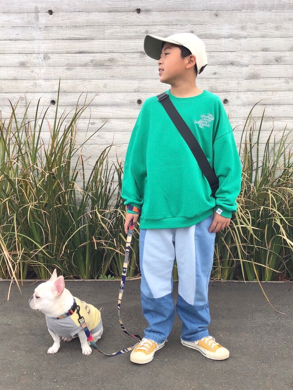 グリーン系のスウェット、ブルー系のデニムパンツ、ブラック系のショルダーバッグを着用したキッズの春コーディネートの1枚目の写真