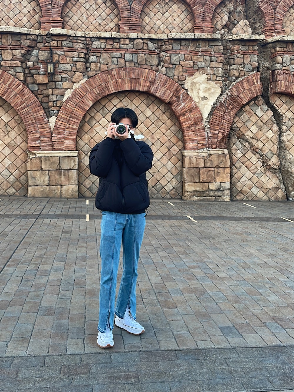 ブラック系のダウンジャケット/コート、ブルー系のその他パンツ、ホワイト系のスニーカーを着用したメンズの冬コーディネートの1枚目の写真