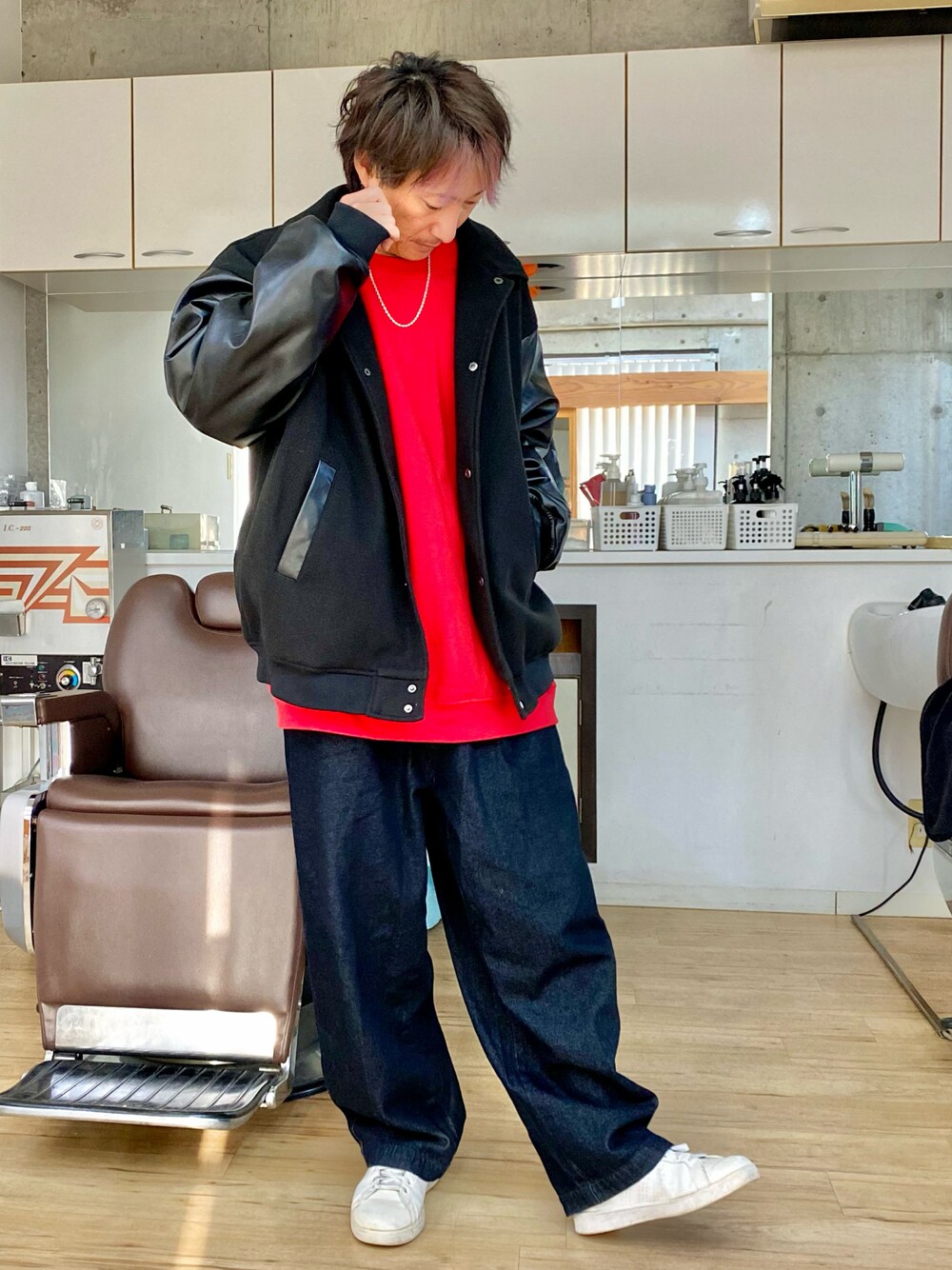 ブラック系のデニムパンツ、レッド系のスウェット、ブラック系のスタジャンを着用したメンズの冬コーディネートの1枚目の写真
