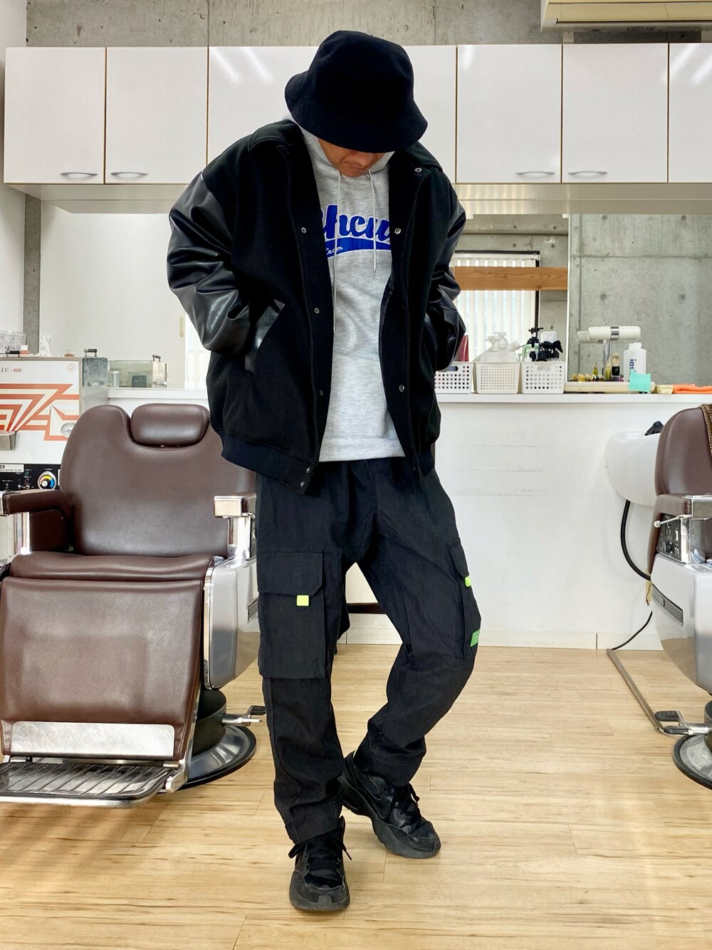 ブラック系のカーゴパンツ、ブラック系のスニーカー、ブラック系のスタジャンを着用したメンズの冬コーディネートの1枚目の写真