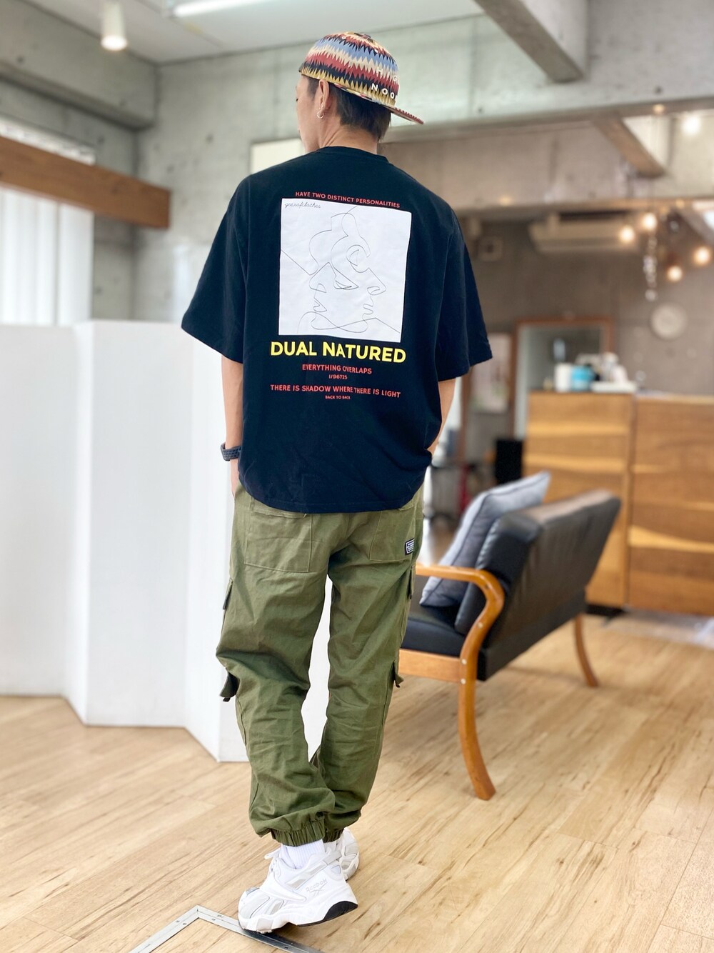 グリーン系のカーゴパンツ、ブラック系のTシャツ/カットソー、ホワイト系のスニーカーを着用したメンズの夏コーディネートの1枚目の写真