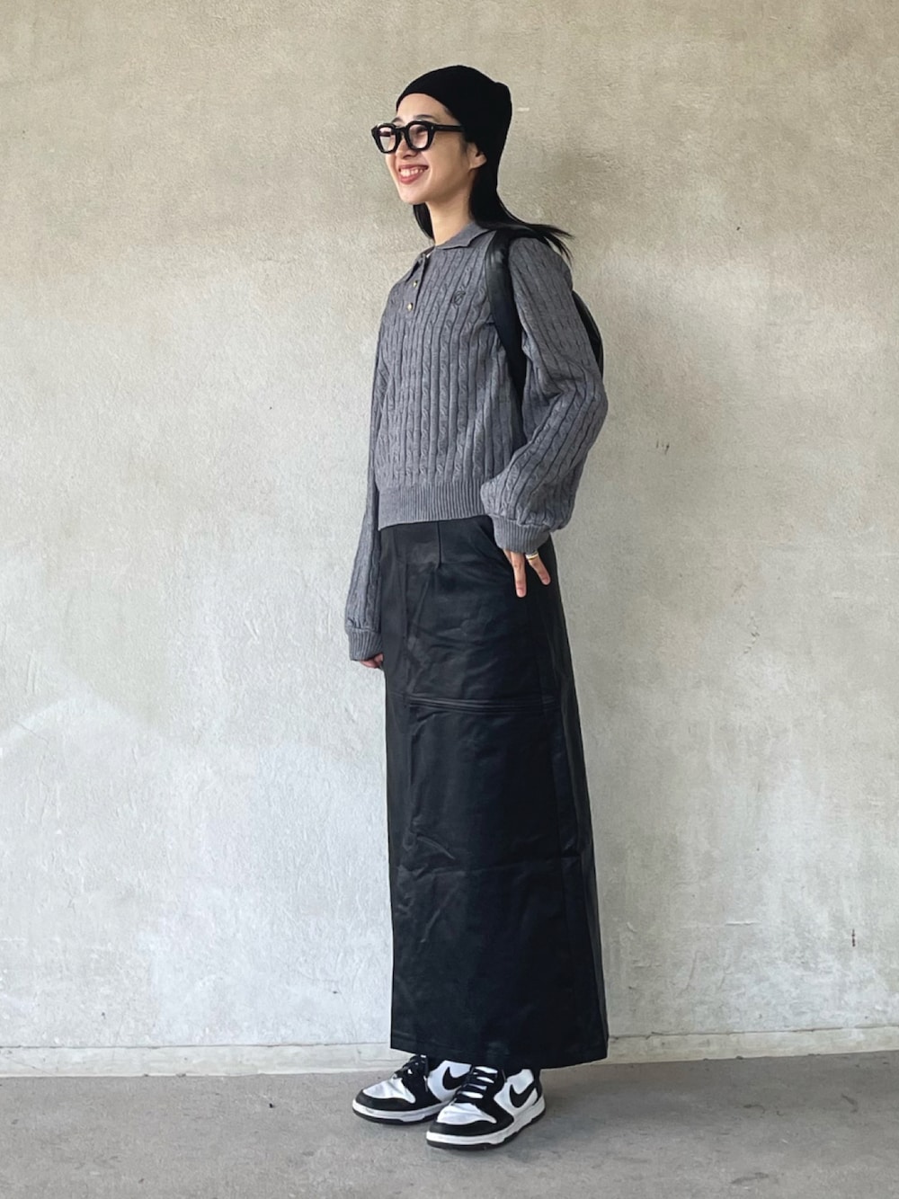 グレー系のニット/セーター、ブラック系のスカート、ホワイト系のスニーカーを着用したレディースの秋コーディネートの1枚目の写真