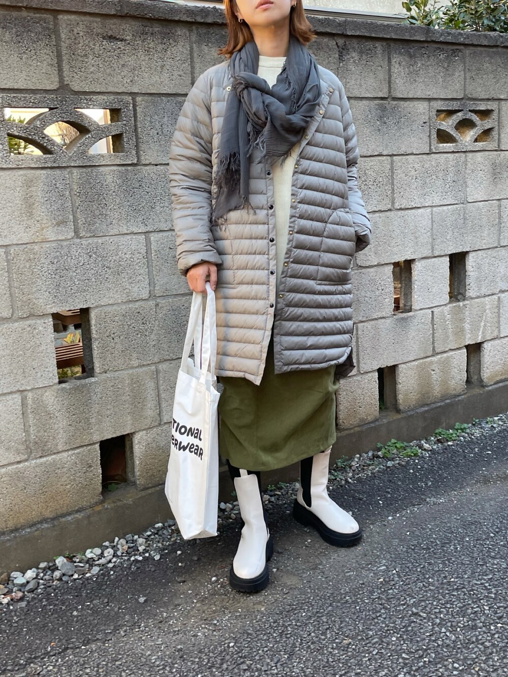 グレー系のダウンジャケット/コート、ベージュ系のニット/セーター、ホワイト系のトートバッグを着用したレディースの秋コーディネートの1枚目の写真