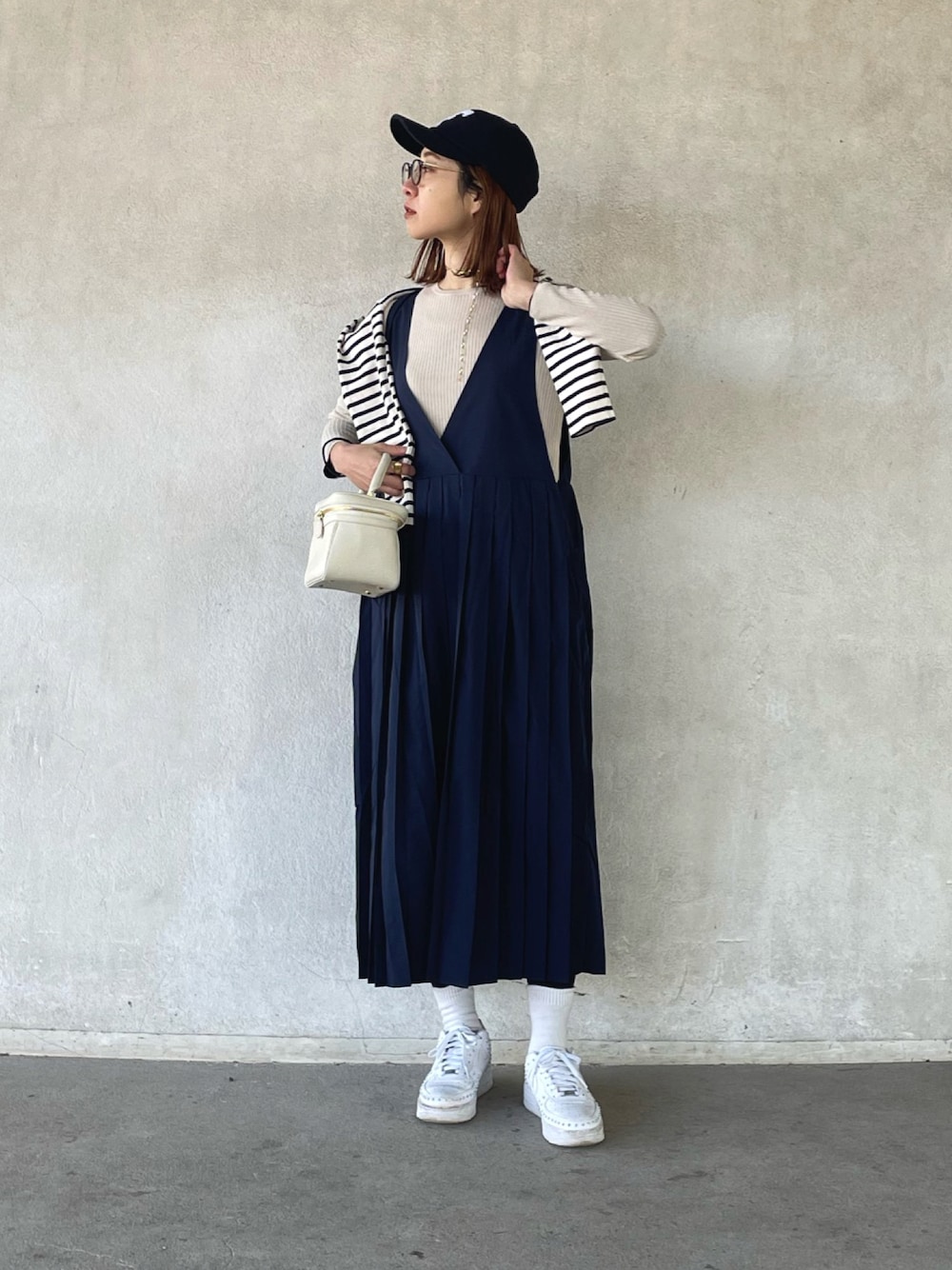 ホワイト系のTシャツ/カットソー、ベージュ系のニット/セーター、ブルー系のジャンパースカートを着用したレディースの冬コーディネートの1枚目の写真