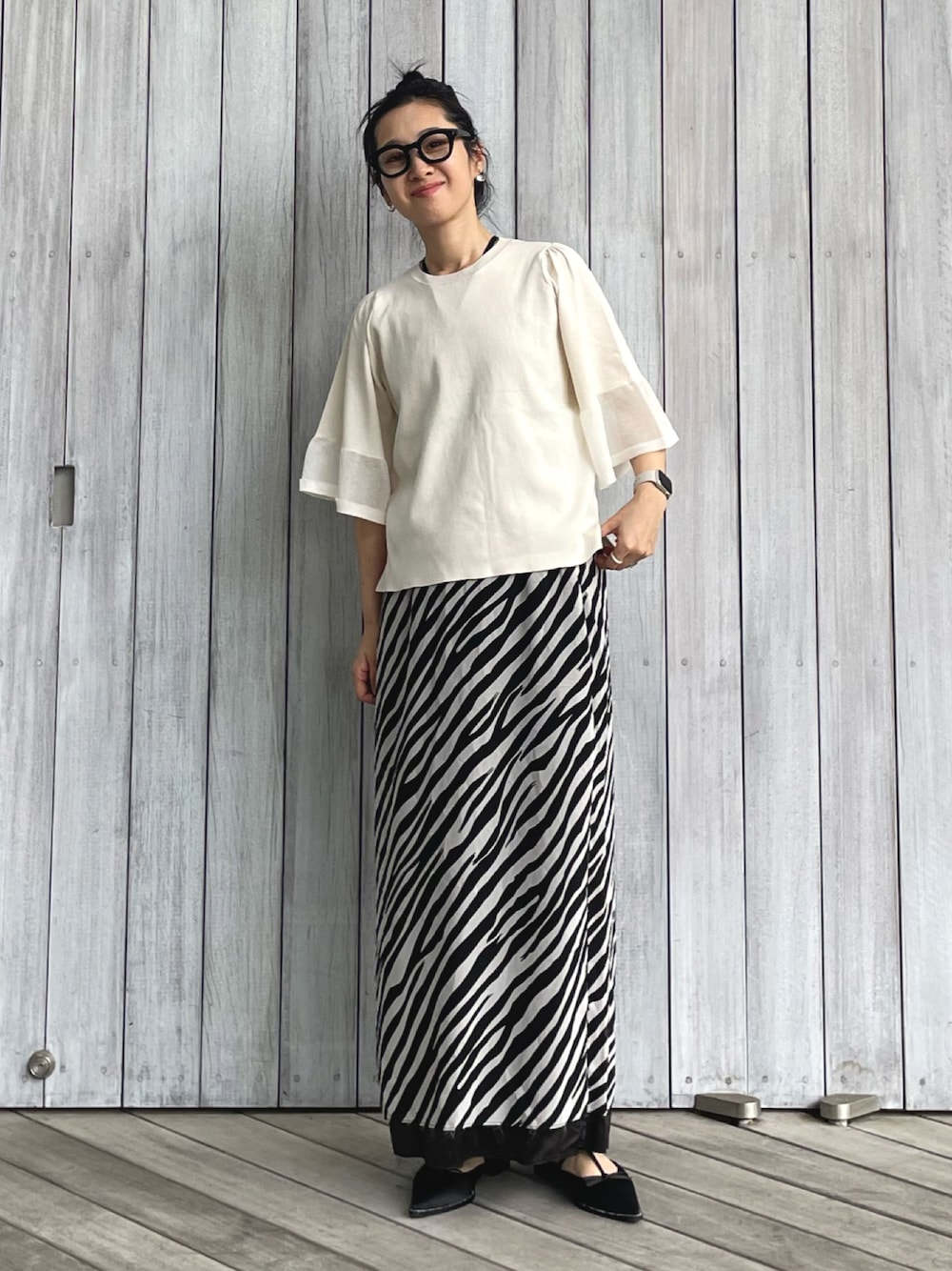 ホワイト系のニット/セーター、ホワイト系のスカート、ブラック系のパンプスを着用したレディースの春コーディネートの1枚目の写真