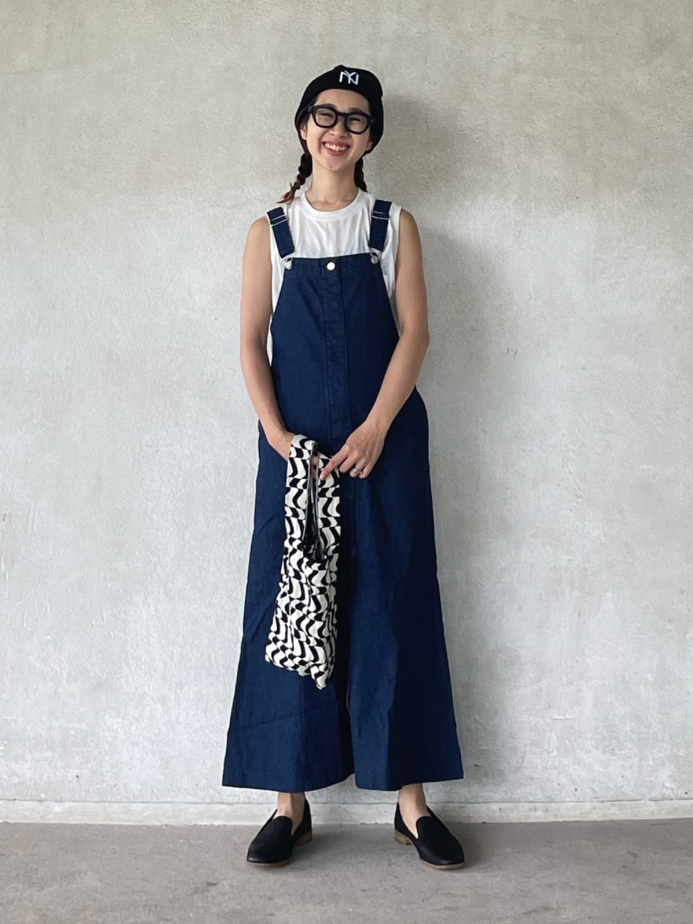 ブルー系のジャンパースカート、ブラック系のトートバッグ、ブラック系のパンプスを着用したレディースの夏コーディネートの1枚目の写真