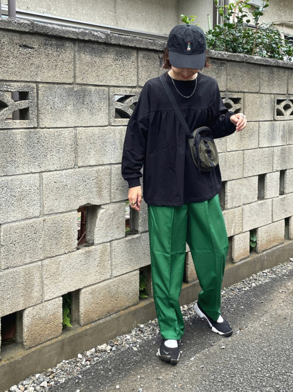 ブラック系のTシャツ/カットソー、グリーン系のスラックス、ブラック系のスニーカーを着用したレディースの秋コーディネートの1枚目の写真