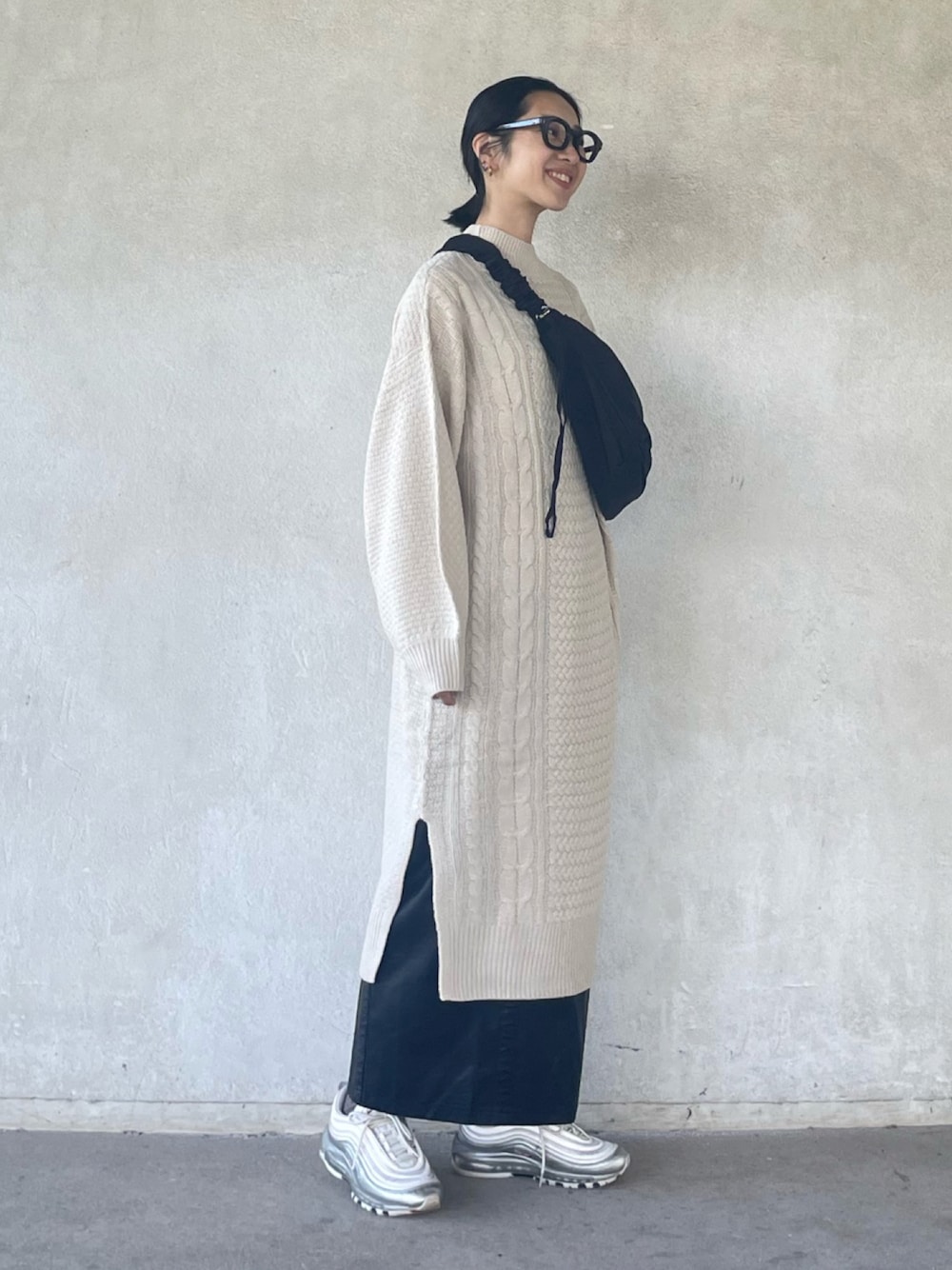 ホワイト系のワンピース、ブラック系のスカート、ブラック系のショルダーバッグを着用したレディースの秋コーディネートの1枚目の写真