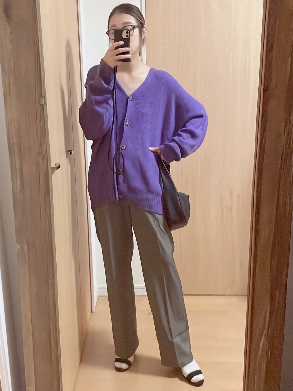 パープル系のカーディガン/ボレロ、ブラック系のハンドバッグ、グレー系のスラックスを着用したレディースの秋コーディネートの1枚目の写真