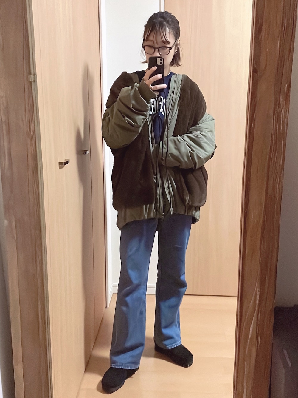 グリーン系のブルゾン、ブルー系のスウェット、ブルー系のデニムパンツを着用したレディースの秋コーディネートの1枚目の写真