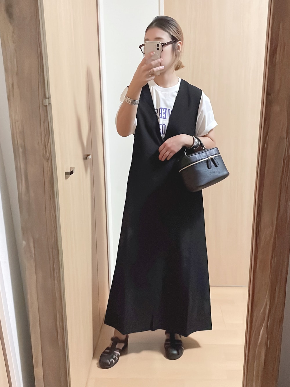 ブラック系のワンピース、ホワイト系のTシャツ/カットソー、ブラック系のサンダルを着用したレディースの夏コーディネートの1枚目の写真