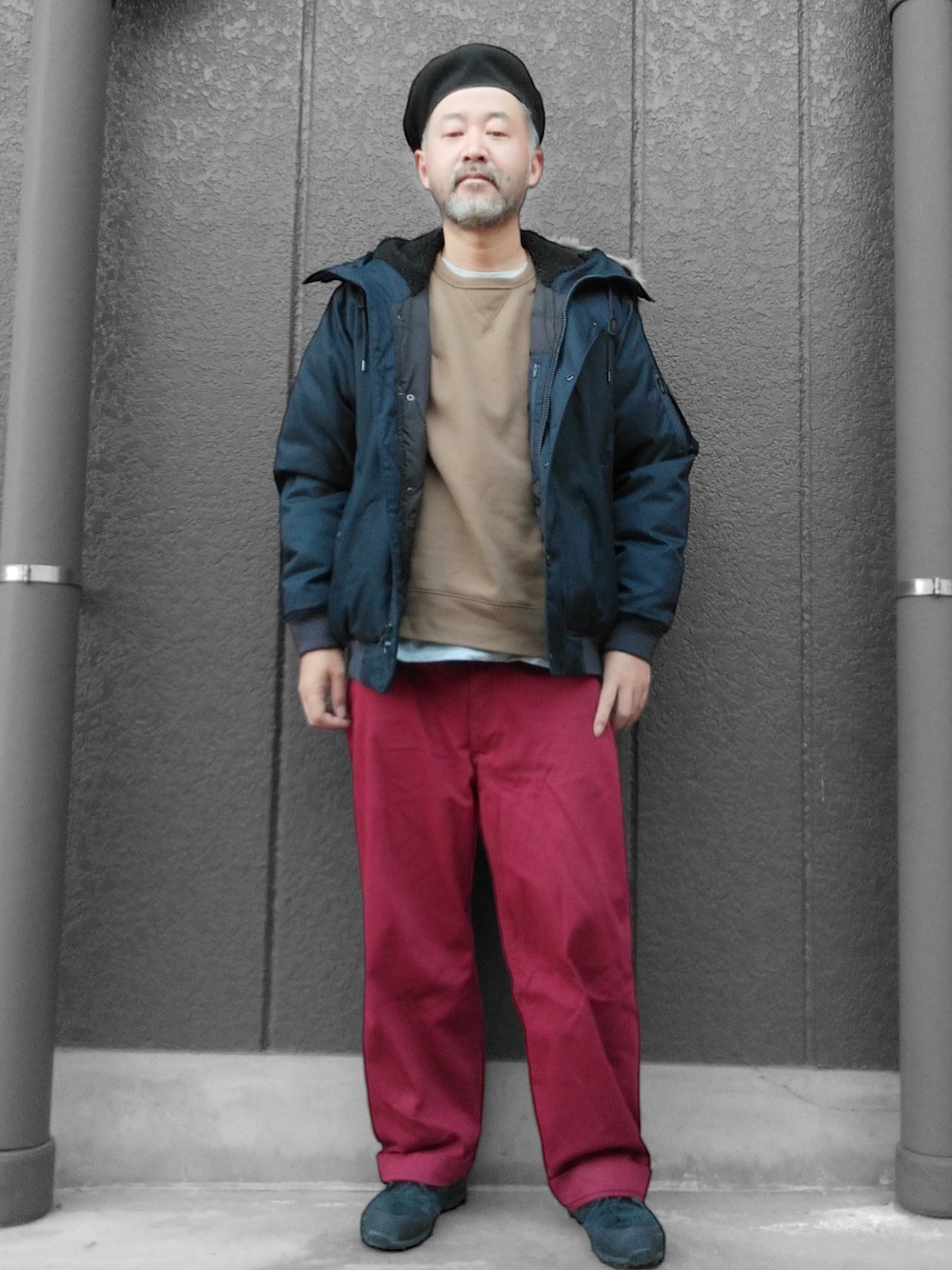 レッド系のチノパンツ、ブルー系のダウンジャケット/コート、ベージュ系のスウェットを着用したメンズの冬コーディネートの1枚目の写真