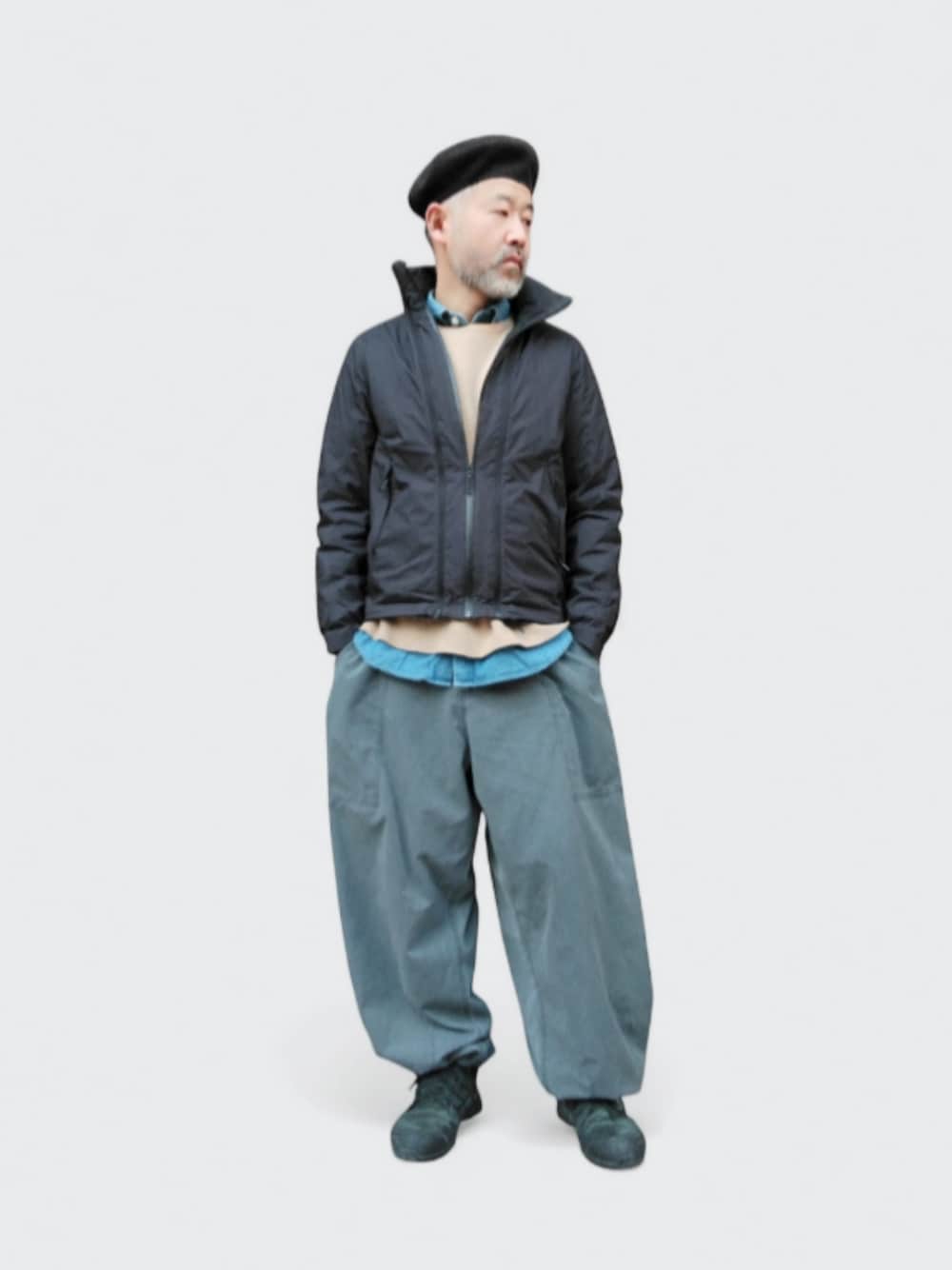 グレー系のパンツ、ブラック系のダウンジャケット/コート、ブラック系のスニーカーを着用したメンズの冬コーディネートの1枚目の写真