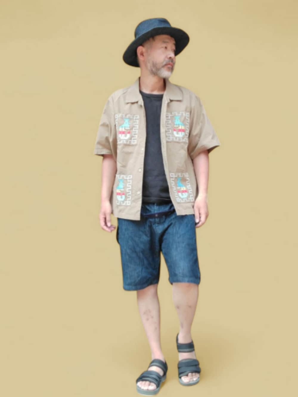 ブルー系のデニムパンツ、ブラック系のサンダル、ベージュ系のシャツ/ブラウスを着用したメンズの夏コーディネートの1枚目の写真